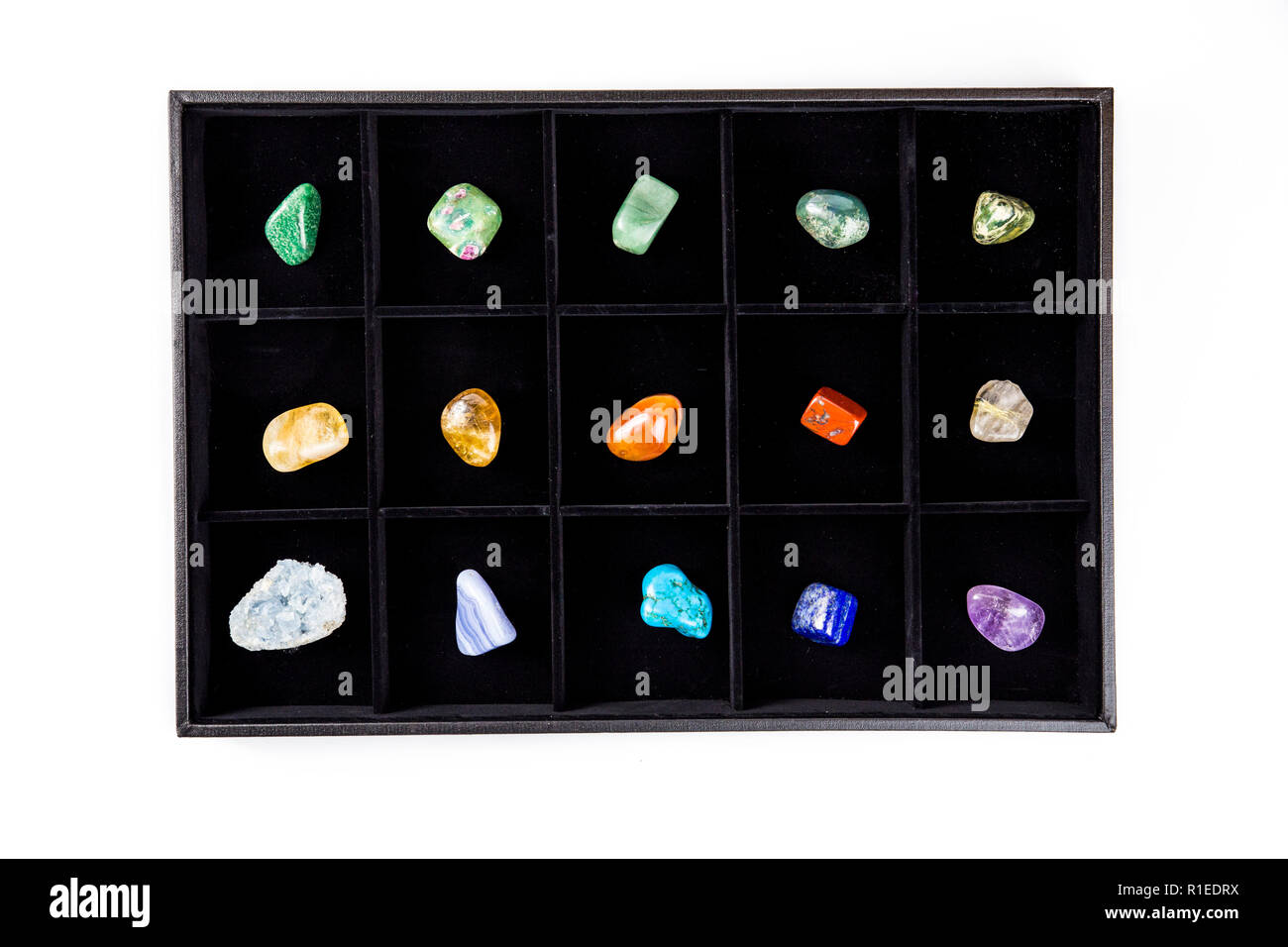 Appartamento vista laici di varietà di coloratissimi semi pietre preziose cristalli nella casella di organizer ordinati dal colore isolato sul nero. Foto Stock