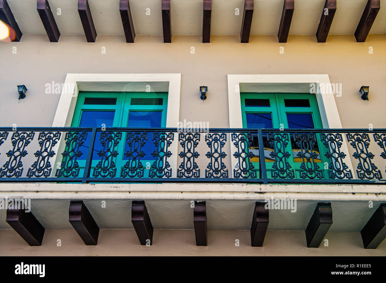 Balcone con decorativi in metallo ringhiera e due finestre di vetro in  cornici verdi sul muro intonacato background in San Juan, Porto Rico. La  simmetria e la geometria di urban concept. Costruzione