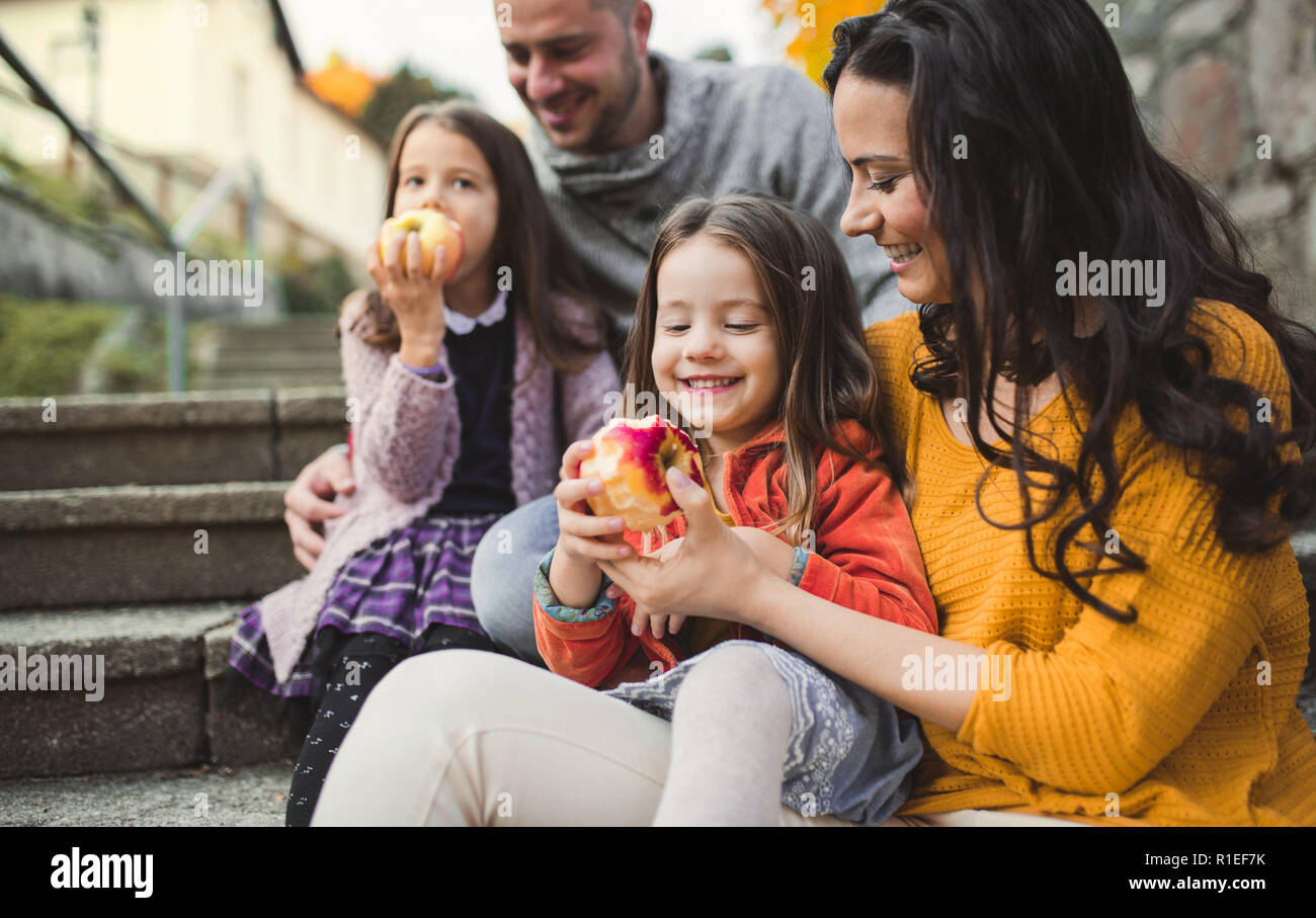 Un Ritratto di giovane famiglia con due bambini piccoli in città in autunno. Foto Stock