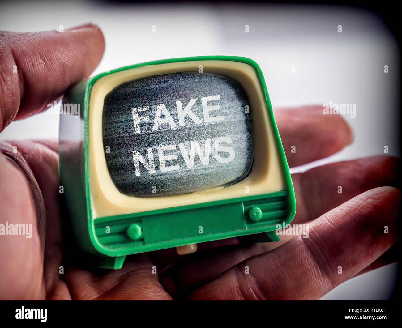 Mano trattiene TV in miniatura, fake news metafora, immagine concettuale Foto Stock