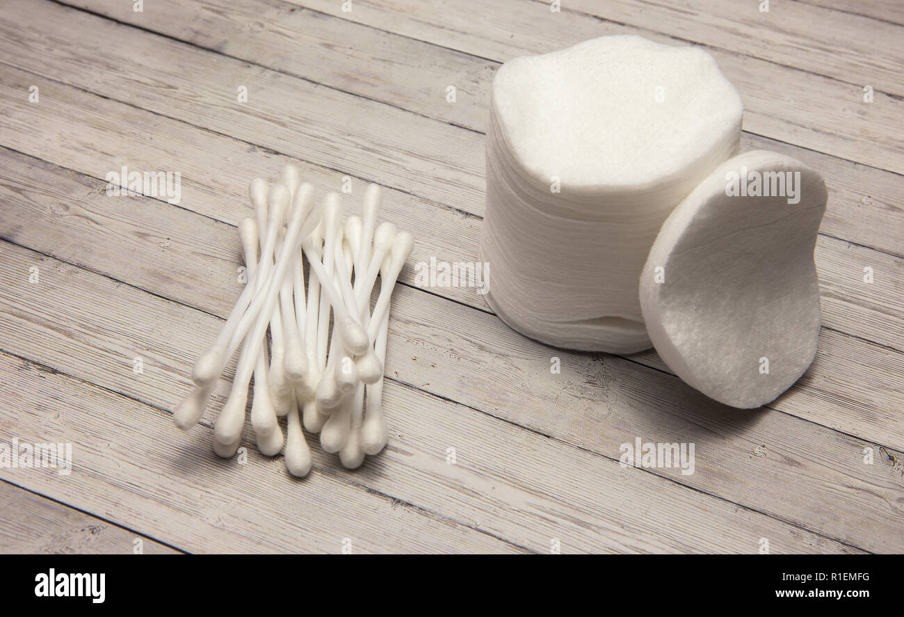 Pulire batuffoli di cotone e bastoncini su uno sfondo di legno Foto Stock