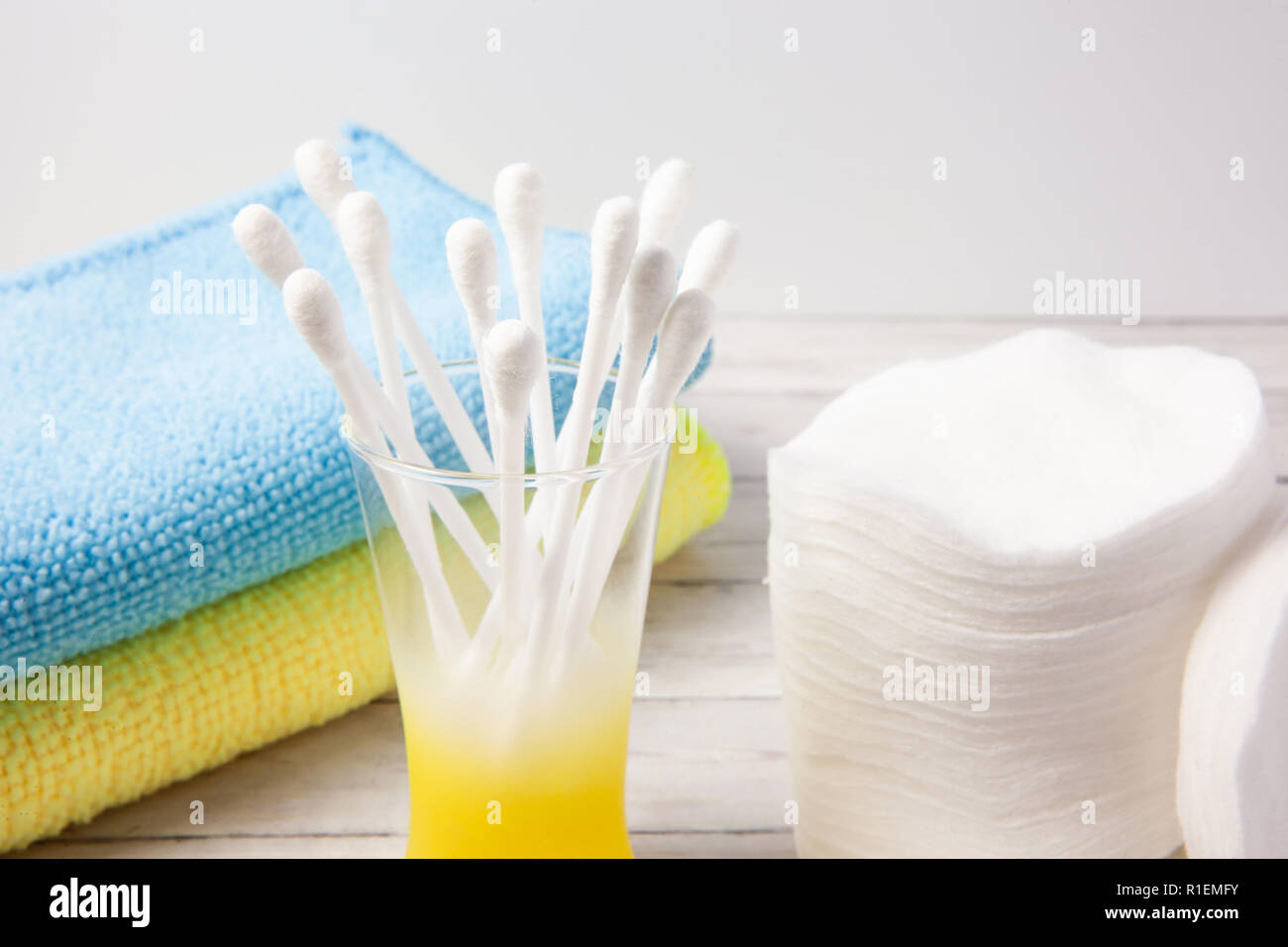 Tamponi di cotone e si inceppa in un vetro su uno sfondo luminoso, accanto ad un blu e giallo asciugamano, close-up Foto Stock