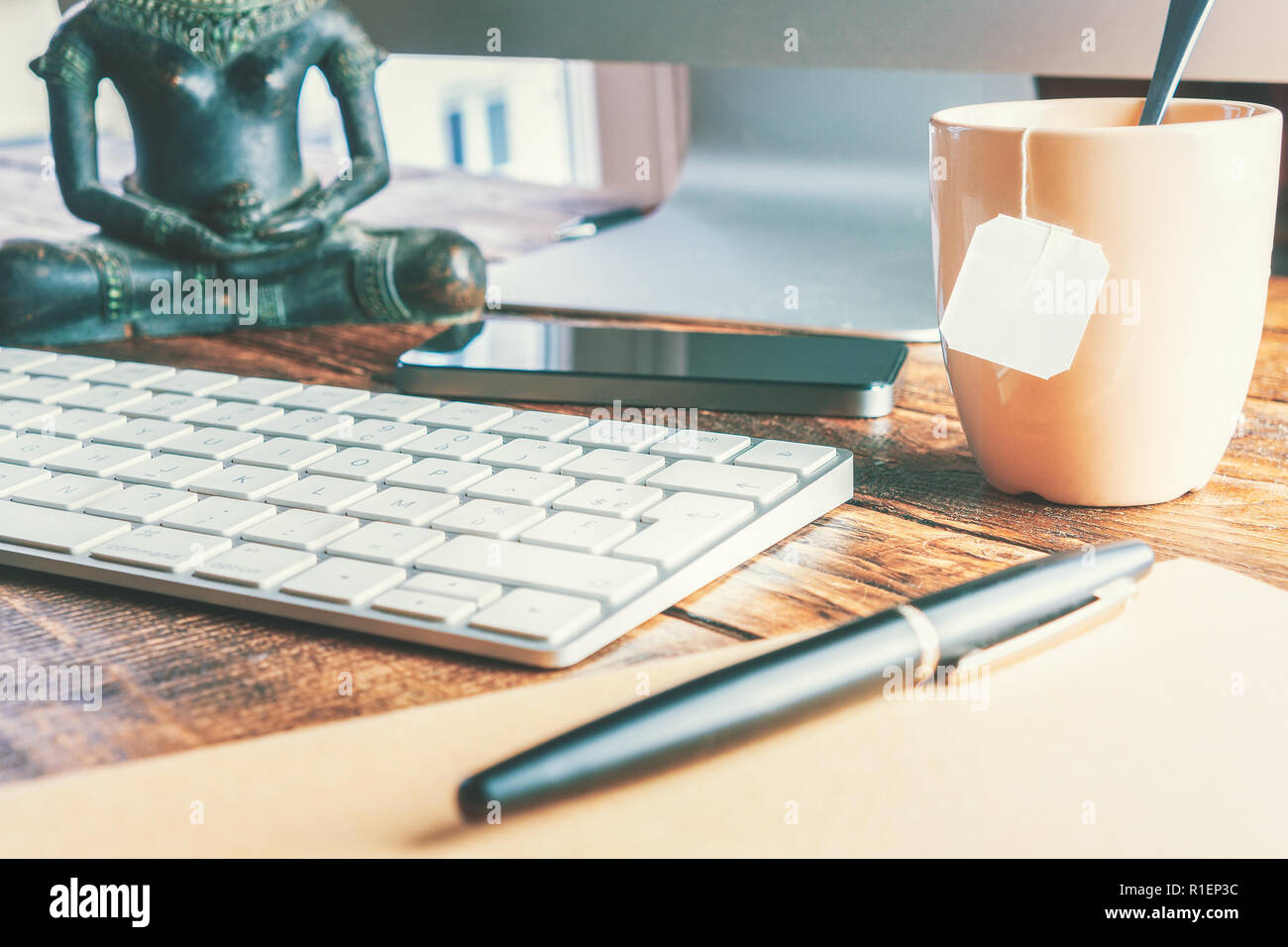 Scrivania da ufficio di close-up con tastiera e una tazza di tè. Lavoro concetto di ufficio. Foto Stock