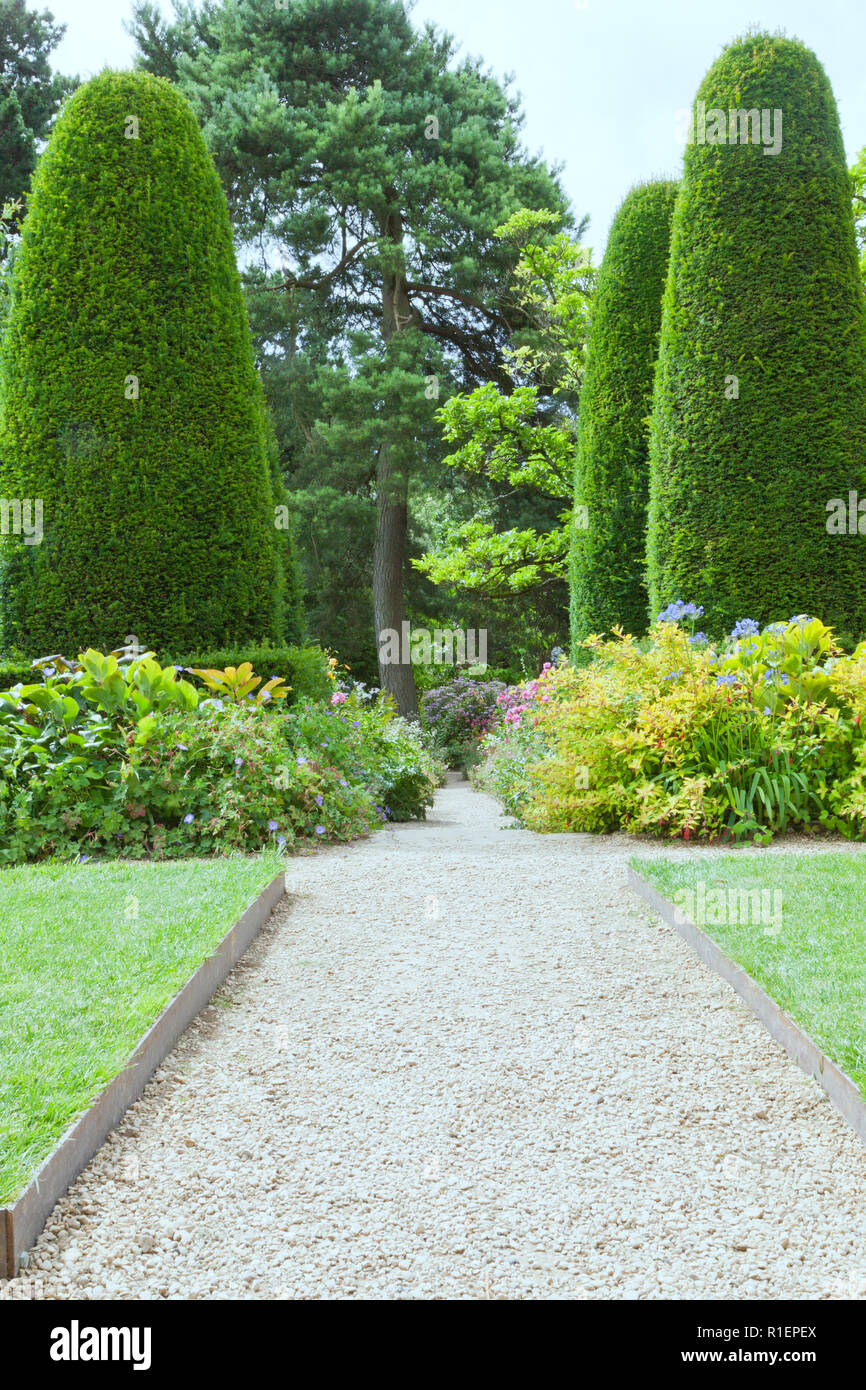 Ghiaia percorso a piedi in fioritura giardino estivo tra fiori, arbusti e alberi . Foto Stock