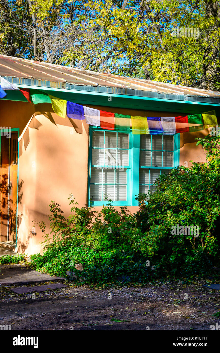 Vista parziale di una semplice casa adobe turchese con rivestimento di vernice accentati con preghiera tibetano bandiere colorfully visualizzato durante il tramonto a Santa Fe, NM Foto Stock