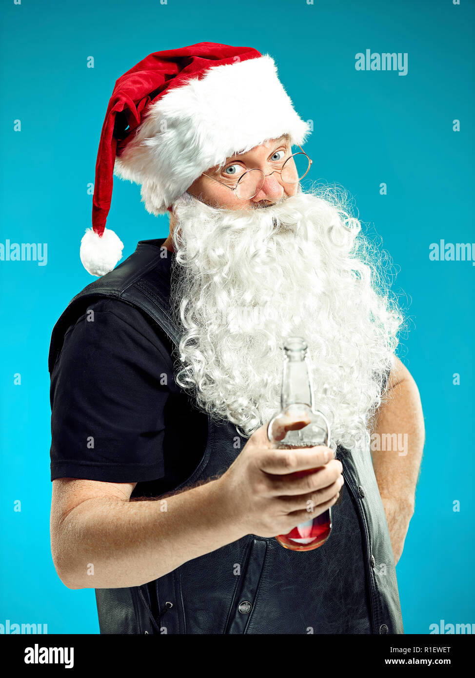 Ritratto di uomo in Santa Claus Costume - con un lussuoso barba bianca, Santa's Hat e un costume rosso a rosso di sfondo per studio con birra Foto Stock