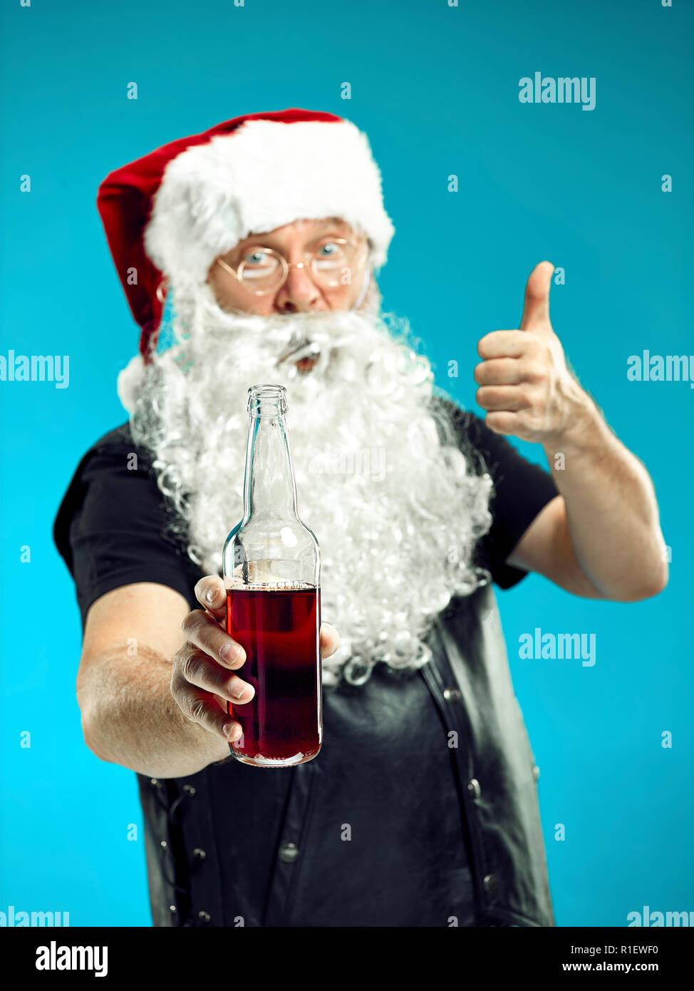 Ritratto di uomo in Santa Claus Costume - con un lussuoso barba bianca, Santa's Hat e un costume rosso a rosso di sfondo per studio con birra Foto Stock