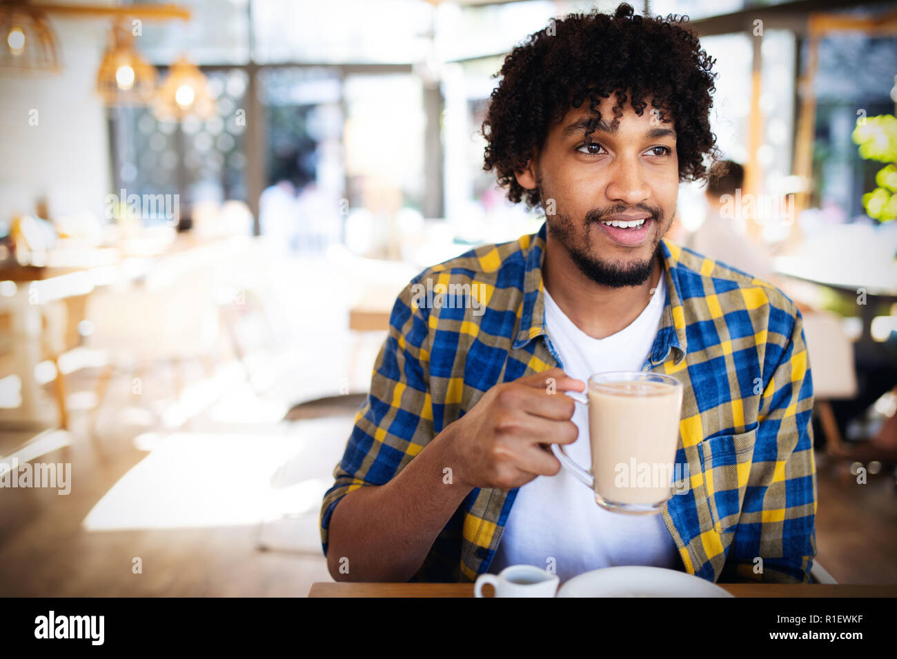 Bel giovane africano di bere una tazza di caffè ad un cafe Foto Stock