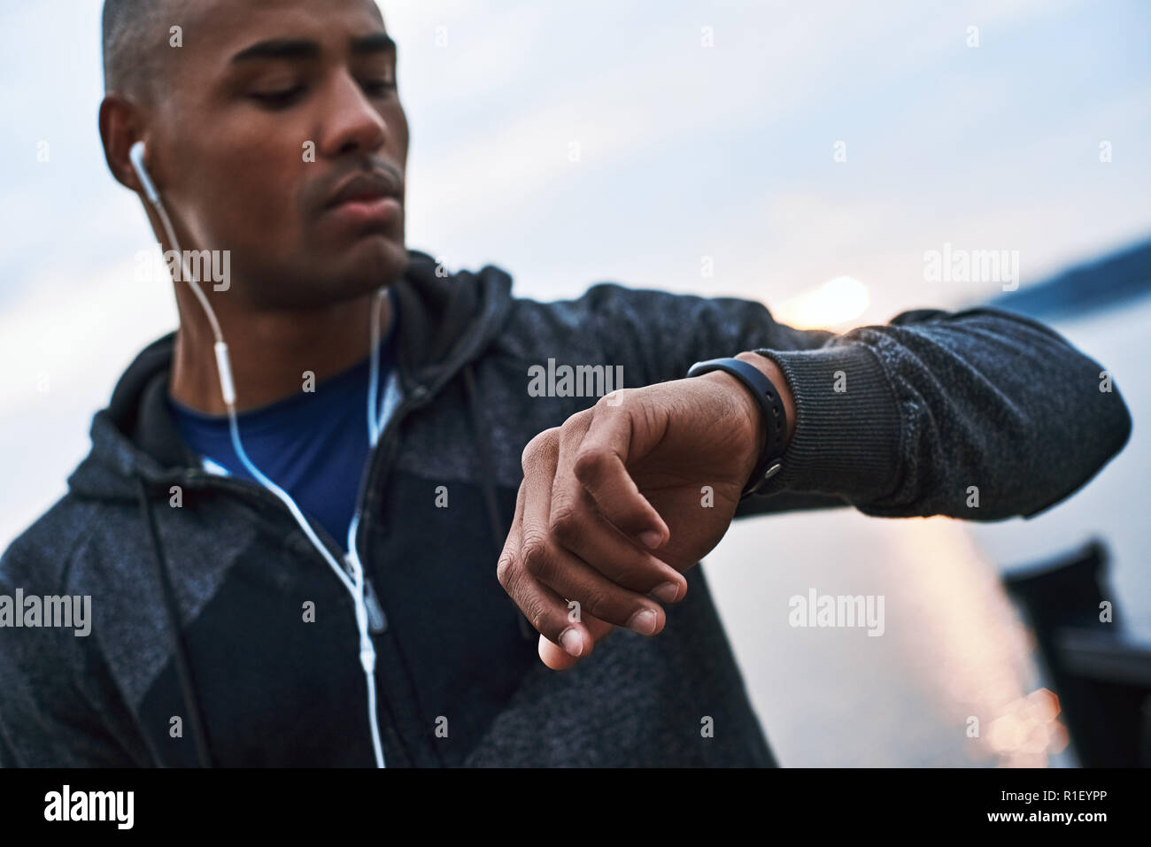 Giovane africano modello guarda al suo smartwatch a distanza traccia ciò che egli aveva eseguito Foto Stock