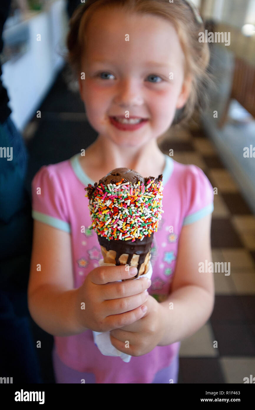 Felice ragazza godendo di un cono gelato con un pizzico Foto Stock