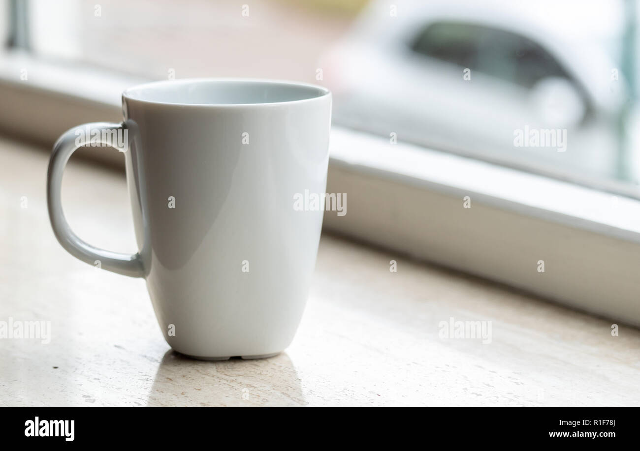 Tazza bianca su un contatore marmer accanto alla luce della finestra. con copia spazio a sinistra su per il testo e le immagini. Foto Stock