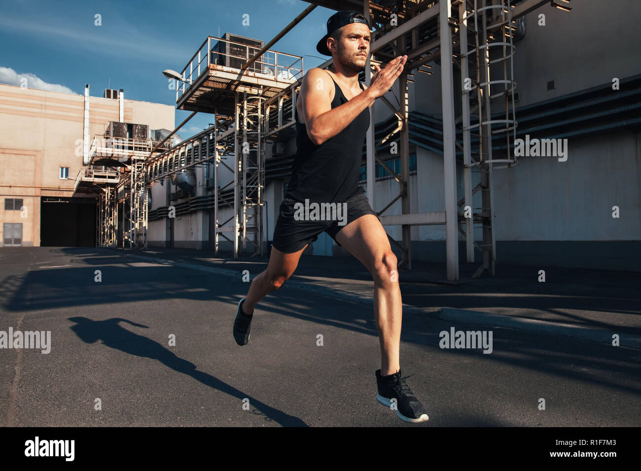 Uomo sportivo corre veloce in città industriale dello sfondo. Sport ed atletica, fitness, attività di jogging Foto Stock