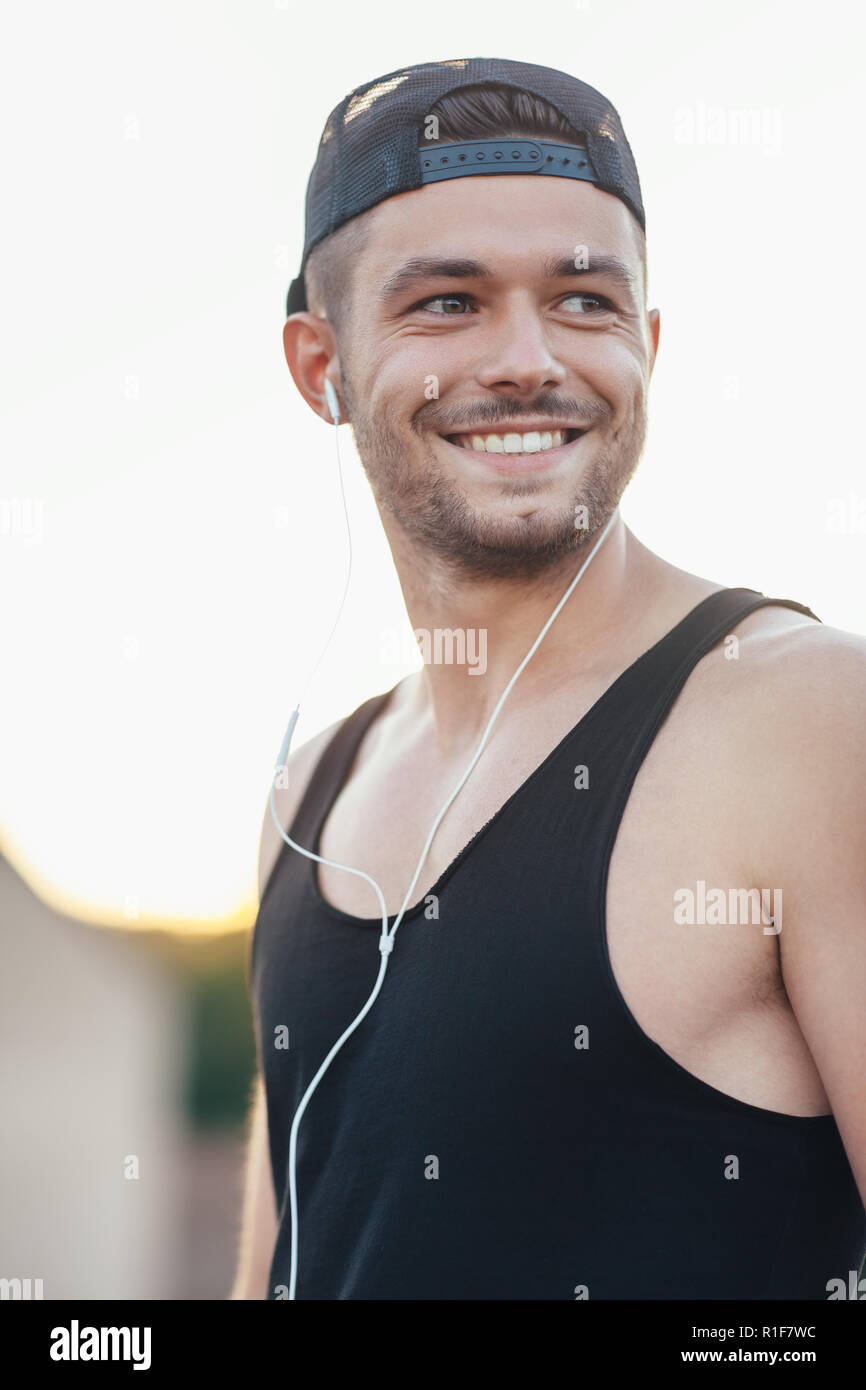 Bel uomo sorridente nelle cuffie per ascoltare musica all'aperto Foto Stock