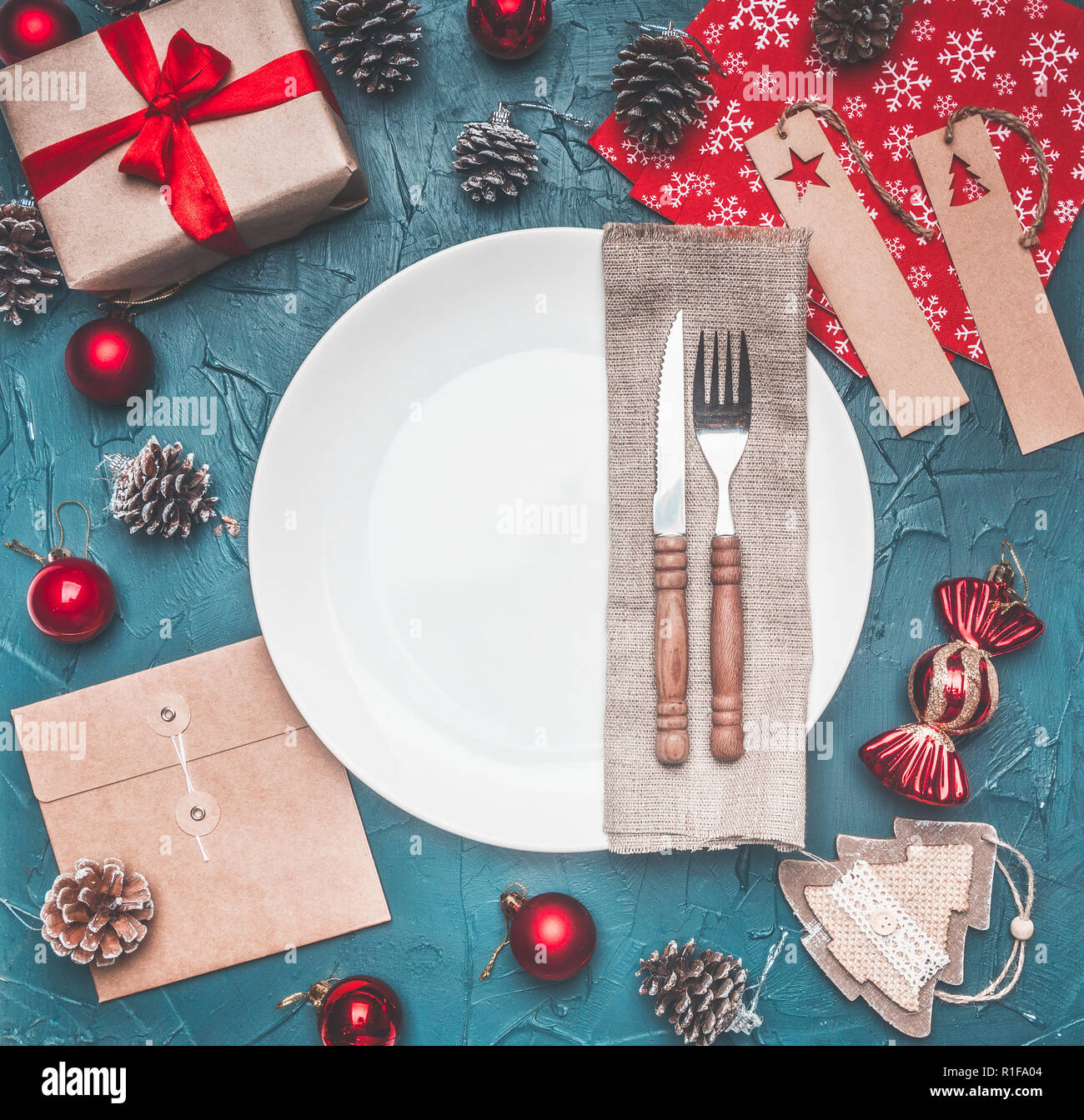 Concetto di natale, cartolina, confezione regalo giocattoli di Natale e coni, su uno sfondo grigio, foderata attorno ad una piastra bianca Foto Stock