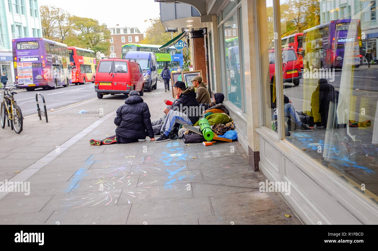 Gruppo di persone senzatetto in seduta shop portali e finestre in North Street Brighton Regno Unito Foto Stock