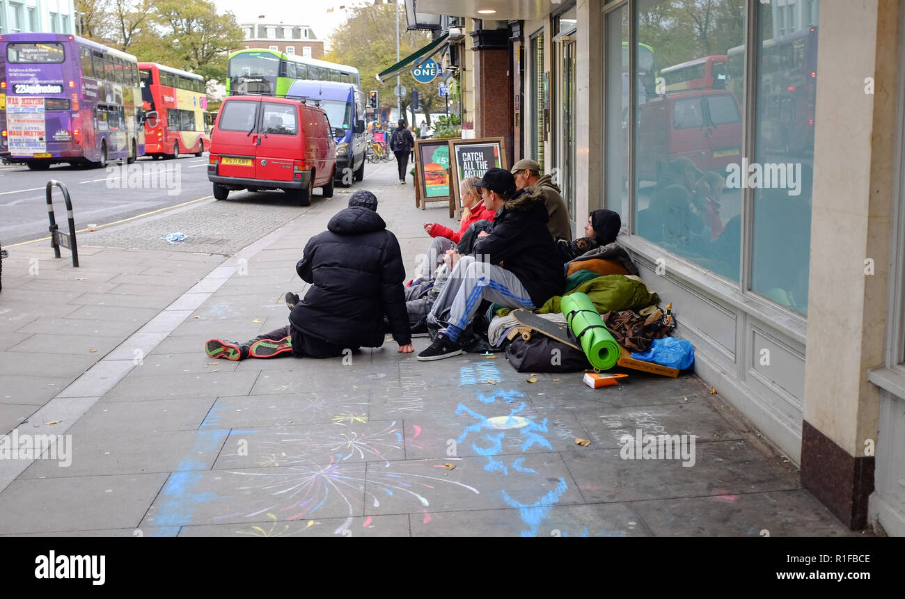 Gruppo di persone senzatetto in seduta shop portali e finestre in North Street Brighton Regno Unito Foto Stock