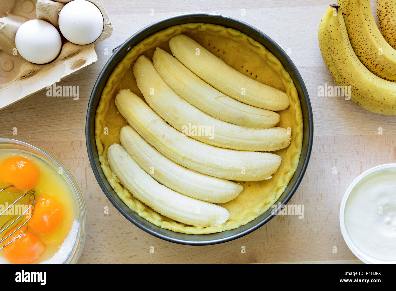 Preparazione Banana torta (cheesecake) rendendo da ingredienti sul tavolo di legno dello sfondo. Lay piatto. Vista dall'alto. Foto Stock