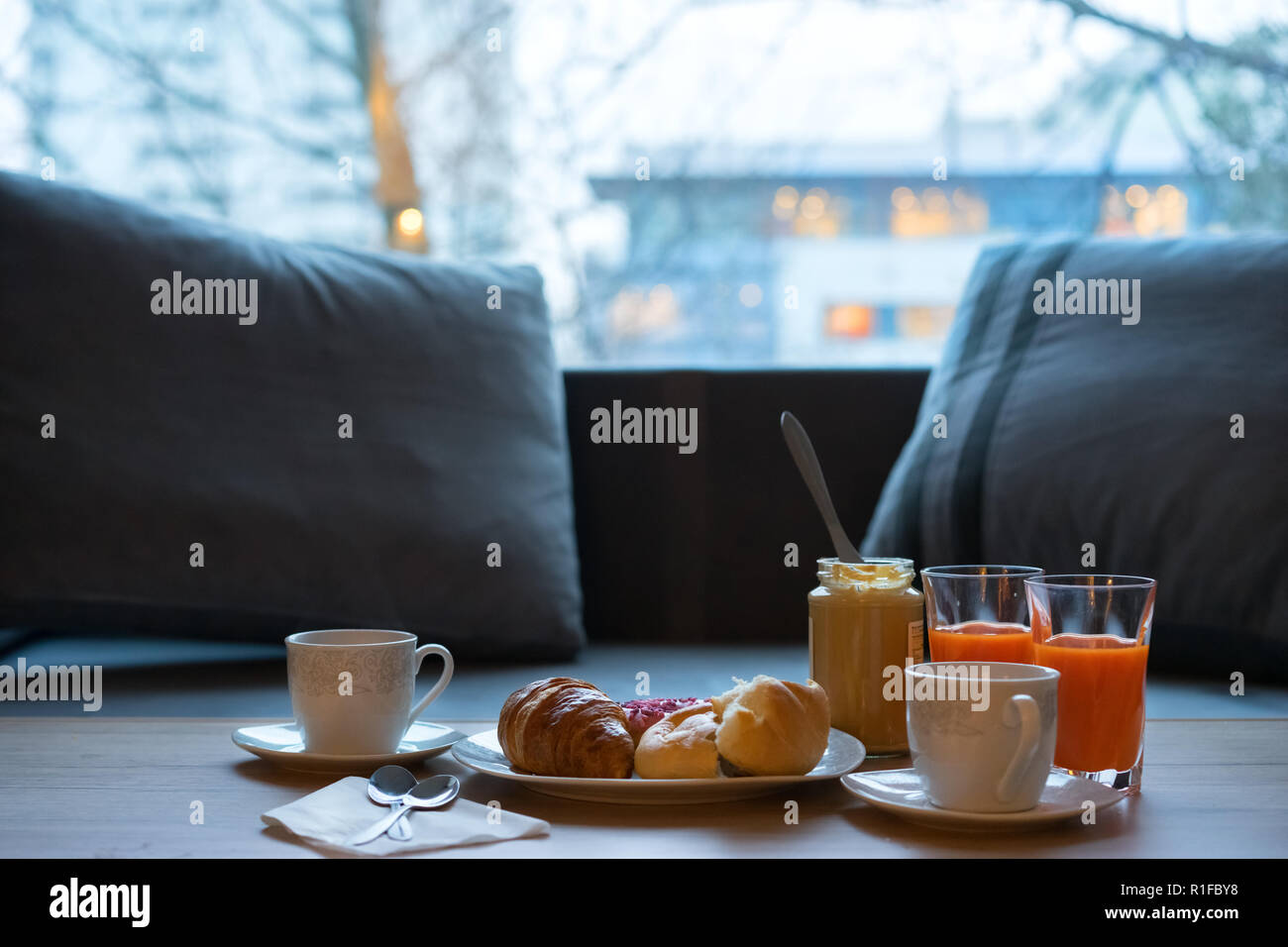 Dark tavolo da cucina con set colazione. Appena sfornate, croissant al burro di arachidi e caffè rustico di legno scuro su sfondo grunge. Foto Stock