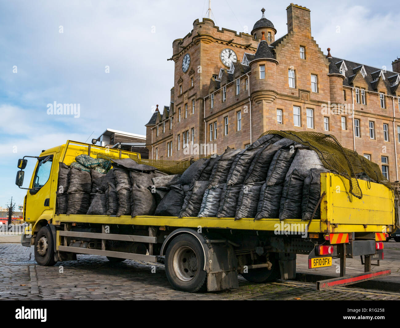 Giallo pianale camion consegna sacchi di carbone con Malmaison Hotel, Tower Place, Leith, Edimburgo, Scozia, Regno Unito Foto Stock
