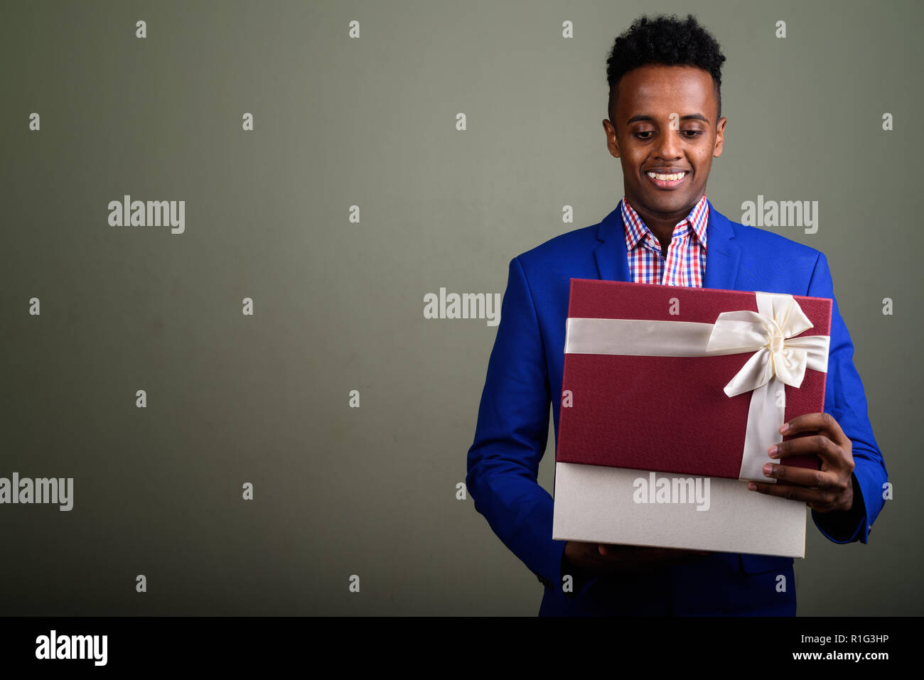 Bel giovane imprenditore africano azienda confezione regalo contro colo Foto Stock