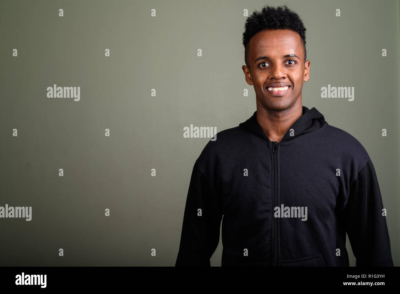 Bel giovane uomo africano indossando hoodie contro backgr colorati Foto Stock