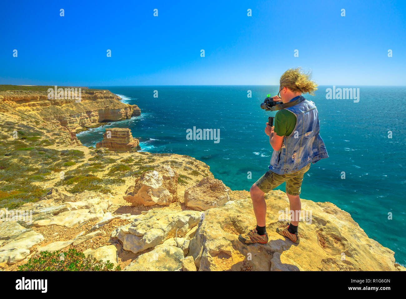 Fotografo di viaggio con sospensione cardanica prende il colpo di Isola di roccia in Kalbarri National Park, Australia occidentale, in una giornata di sole con cielo blu. Professional videomaker prende Foto di Australian Coral Coast. Foto Stock