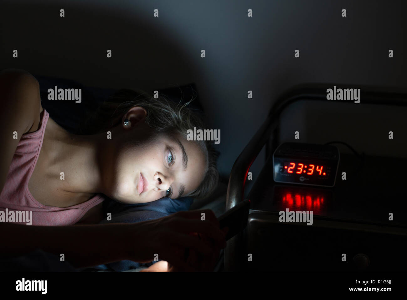 Giovane ragazza a letto fino a tarda notte con il suo smartphone. Mobile o social media addiction Foto Stock