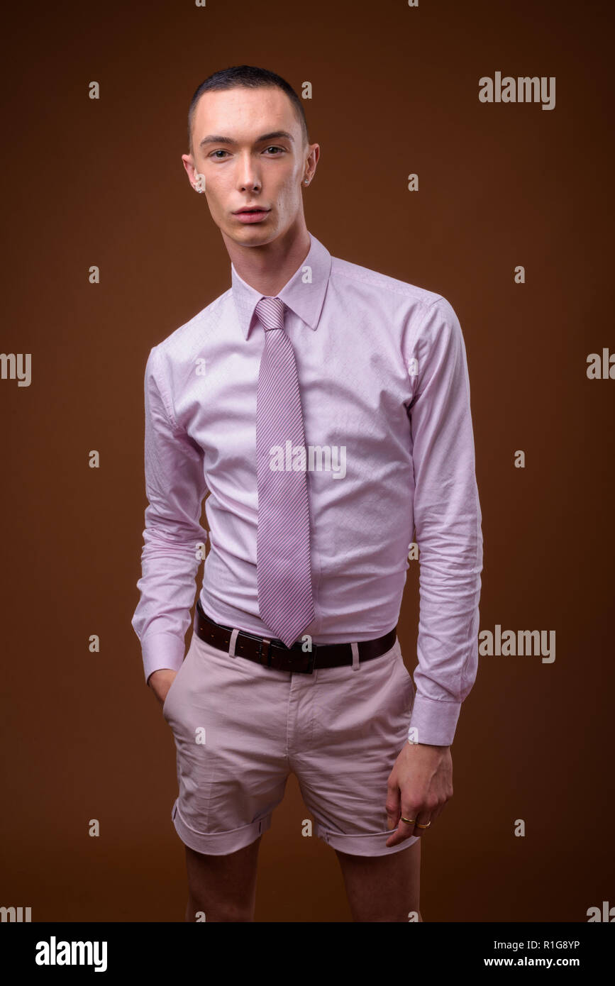 Giovane bello androgino imprenditore contro sfondo marrone Foto Stock