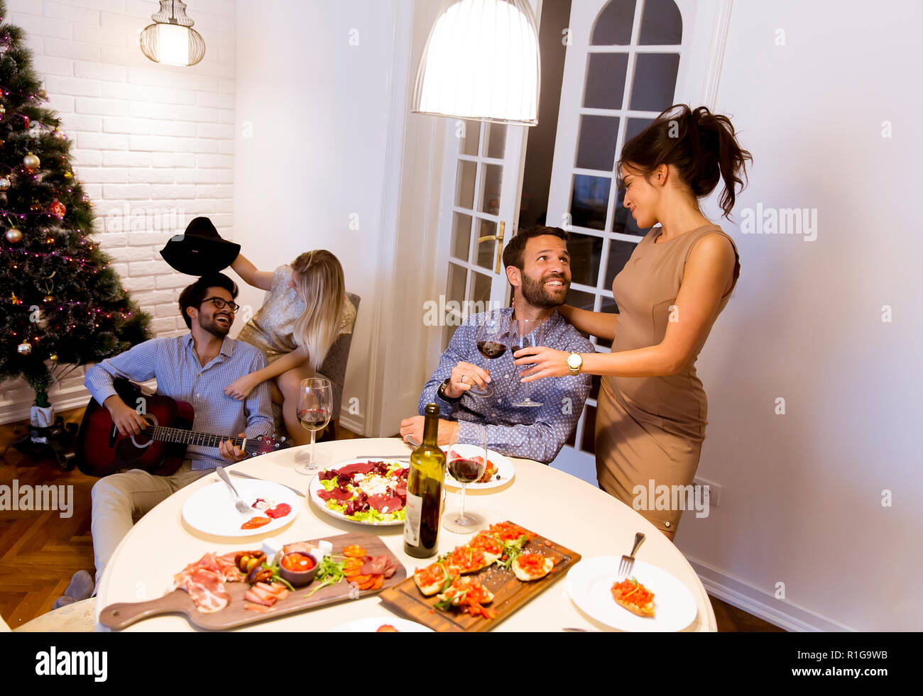 Giovani amici festeggiano il Natale o Capodanno a casa Foto Stock