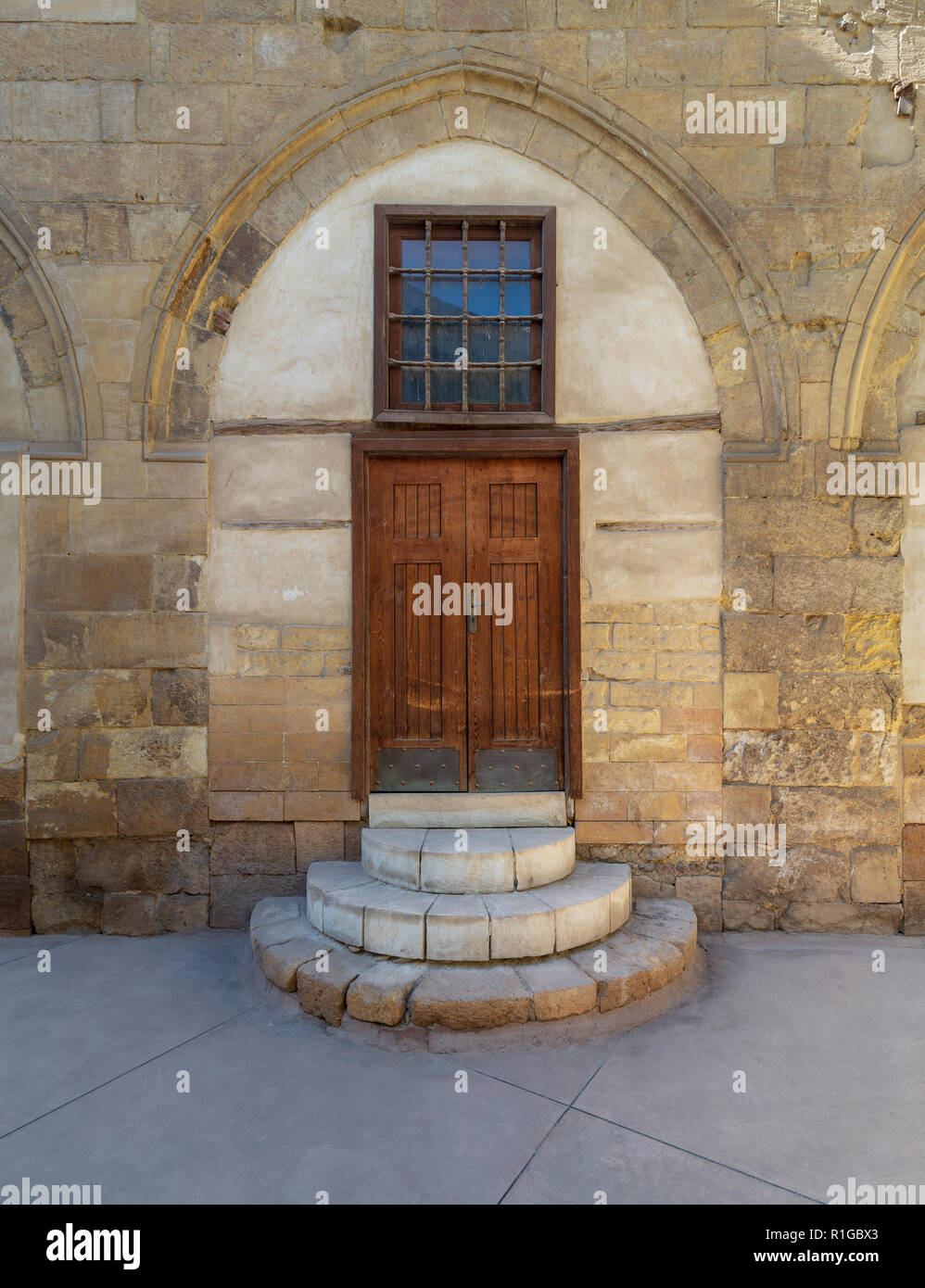 Vecchia porta di legno e finestre incorniciate da mattoni arcuati muro di pietra presso il cortile di al Razzaz casa storica, Darb al Ahmar distretto, vecchio Cairo, Egitto Foto Stock