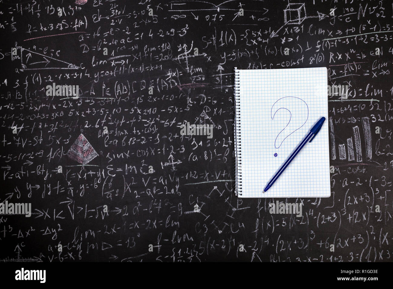 Studente di notebook con una penna e un punto interrogativo sul fondo della scheda con esempi e formule Foto Stock