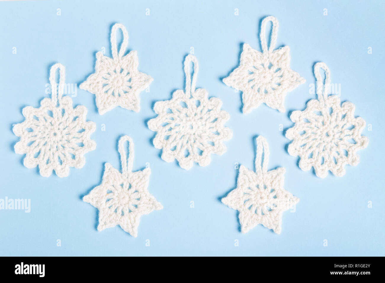 Composizione di natale di maglia fiocchi di neve bianca e stelle su sfondo blu. Vista superiore, piana, laici copia spazio. Foto Stock