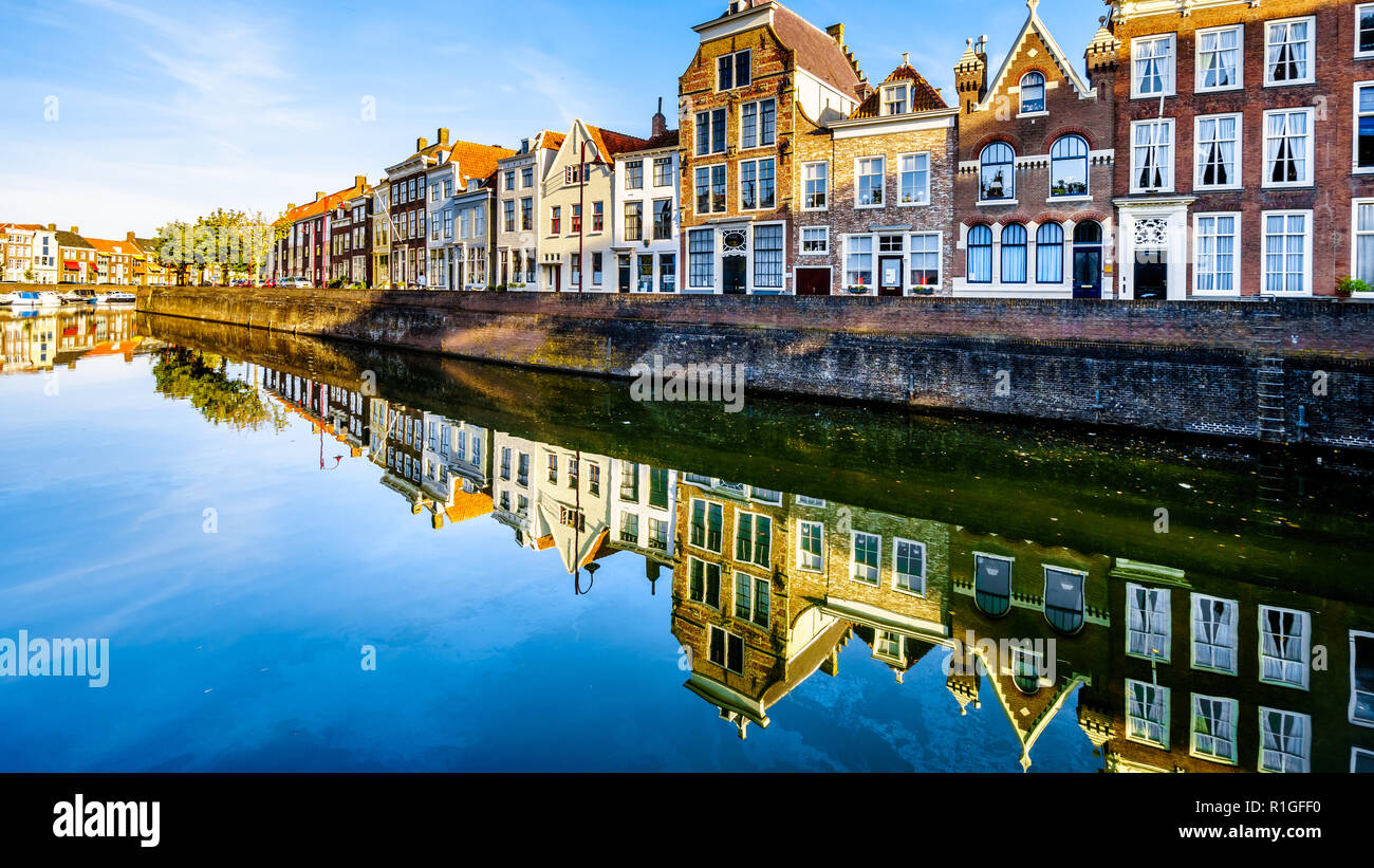 Tramonto su una fila di case che si riflette sulla superficie dell'acqua di un canale nel centro storico della città di Middelburg nella provincia della Zeeland, Olanda Foto Stock