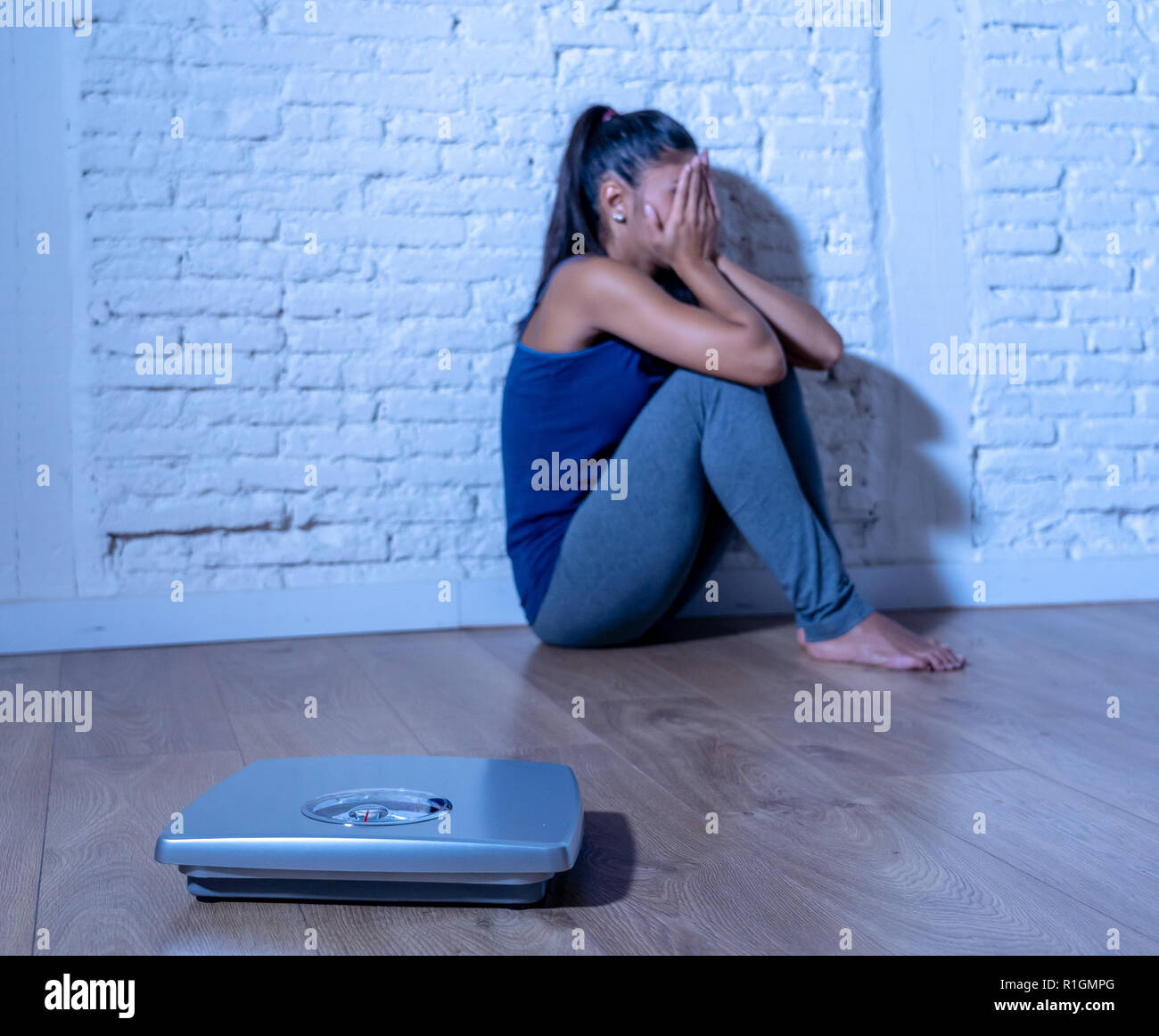 Giovane adolescente anoressica donna seduta da sola sulla terra guardando la scala preoccupata e premuto in dietologia e disturbo alimentare concept Foto Stock