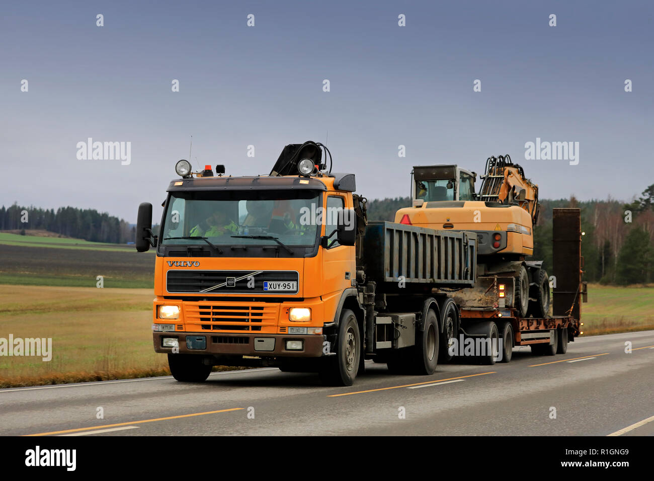 Salo, Finlandia - 9 Novembre 2018: Giallo Volvo Truck cale escavatore Liebherr su autostrada vicino dusktime in autunno nel sud della Finlandia. Foto Stock