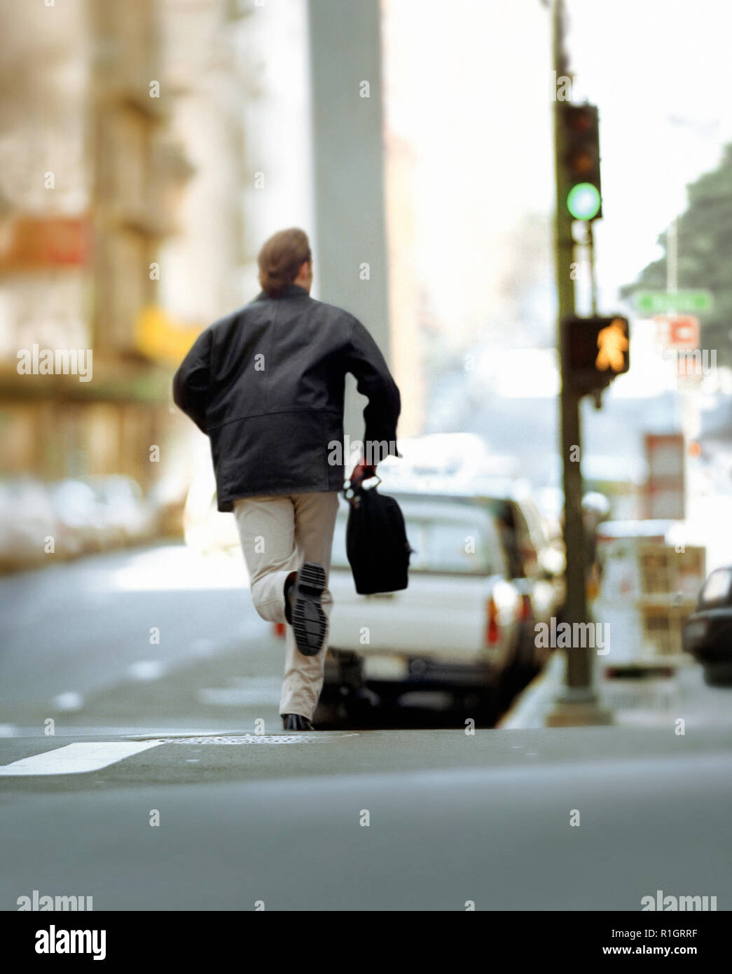 Vista posteriore di un uomo che corre attraverso una strada. Foto Stock