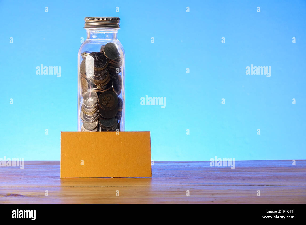 Concetto di risparmio con mason jar,monete e salvadanaio su uno sfondo blu. Foto Stock