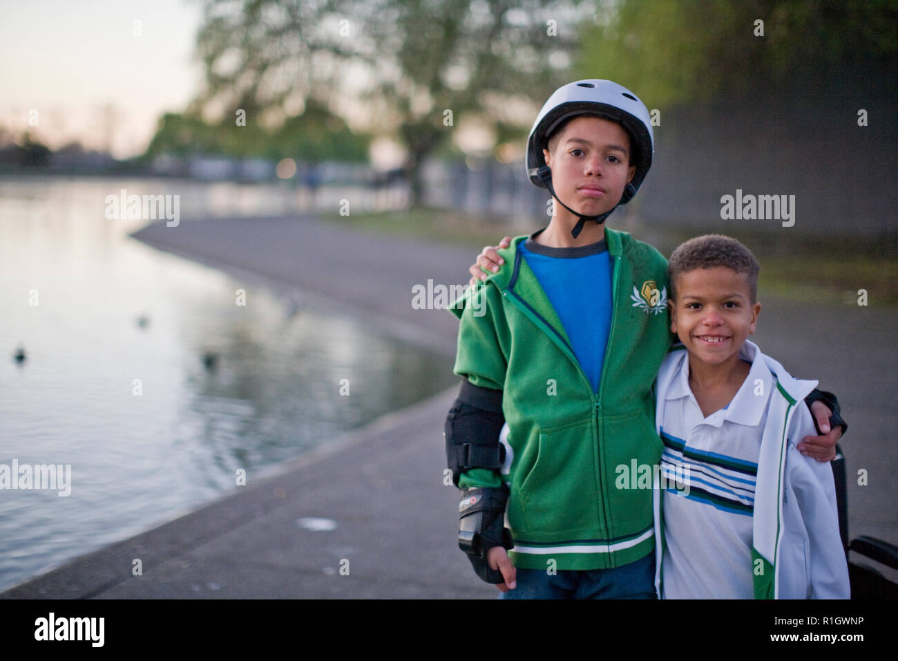 Fratelli in piedi accanto al laghetto sorridente Foto Stock