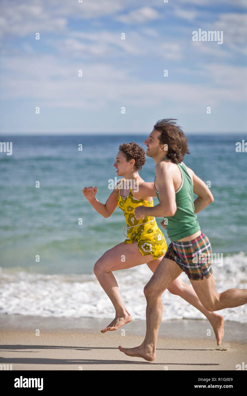 Giovane uomo e donna in esecuzione uno accanto all'altro su una spiaggia. Foto Stock
