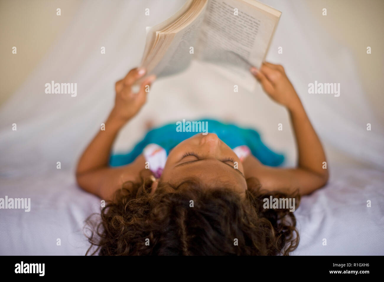 Ragazza giovane la lettura di un libro in una stanza. Foto Stock