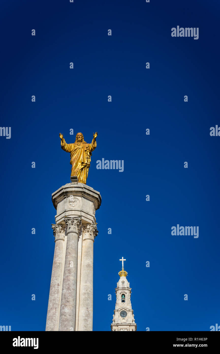 Fatima è il centro della religione cattolica in Portogallo. La statua di Gesù si innalza nella piazza principale della Basilica. Foto Stock