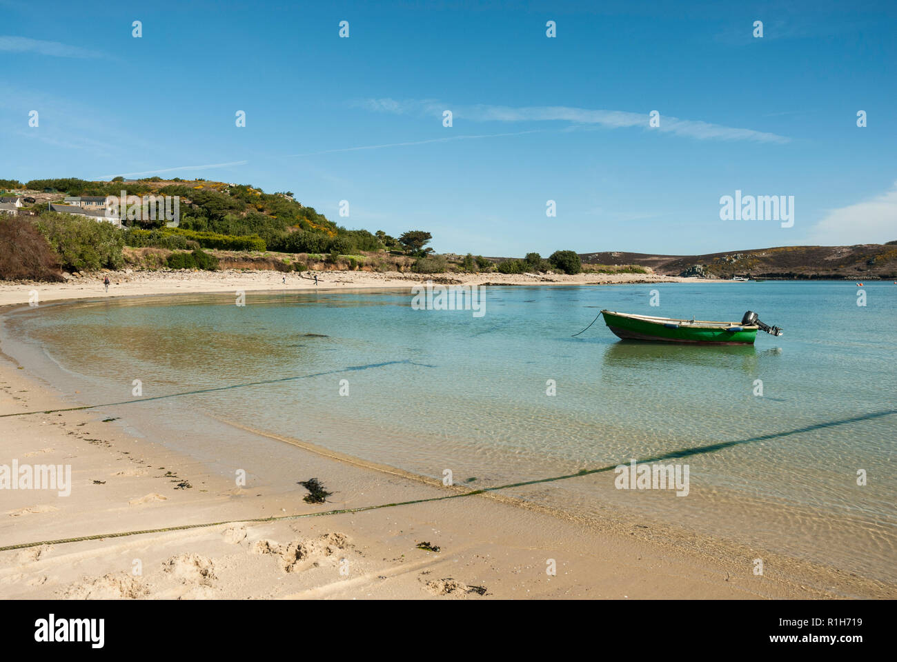 La bellissima spiaggia sabbiosa di chiesa Quay, Bryher in una giornata di sole con cielo limpido mare blu e un blu piccola barca di legno. Foto Stock