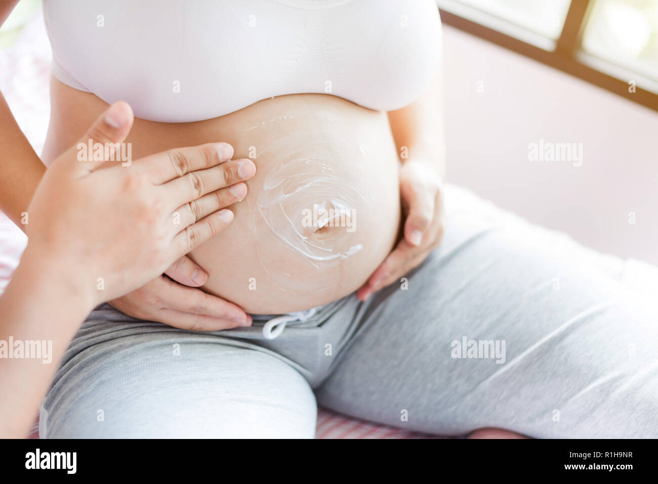 Asian donna incinta con grande pancia. Rilassarsi a casa con il marito. Foto Stock