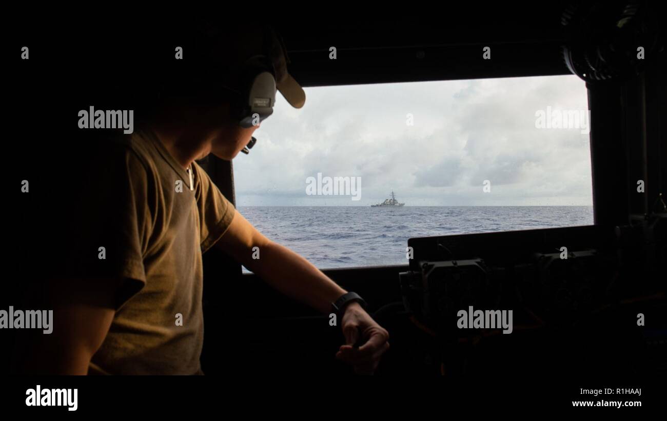 Lt. Joshua Teeman, da Owasso, Oklahoma, assegnato a Costiera squadrone fluviale (CRS) 3, mantiene un contatto visivo sul Arleigh Burke-class guidato-missile destroyer USS Decatur (DDG 73) da un marchio vi motovedetta assegnato a Costiera gruppo fluviale (CRG) 1 det. Guam, Sett. 19, 2018 durante la Valiant scudo 2018. Valiant Shield è un solo negli Stati Uniti, biennale la formazione sul campo di allenamento (FTX) con un focus sulla integrazione di formazione congiunta in un Blu-acqua ambiente tra le forze americane. Questa formazione consente un vero-mondo proficiency nel sostenere forze congiunte attraverso il rilevamento, la localizzazione, tracking e impegnare uni Foto Stock