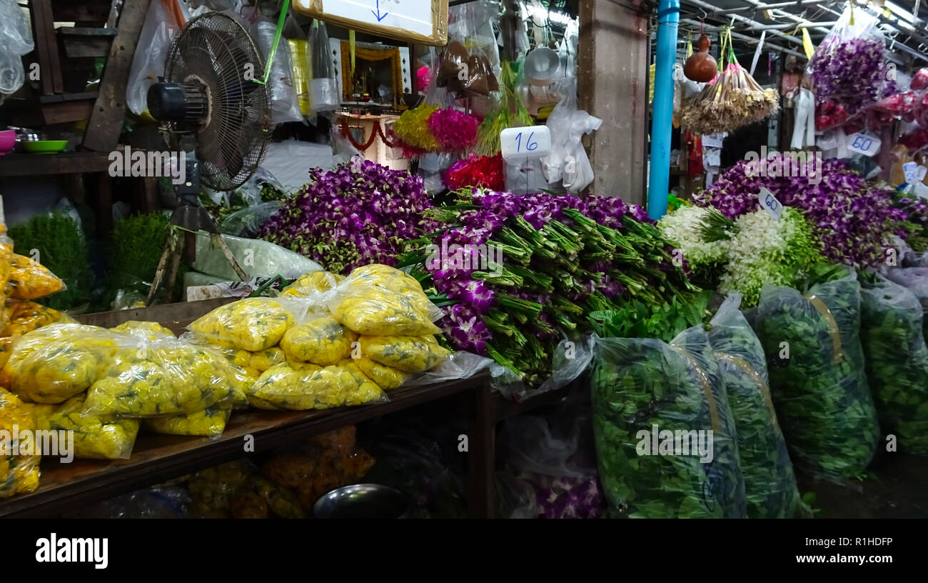 Fiori diversi avvolti in materiale plastico in un mercato coperto in serata a Bangkok Foto Stock