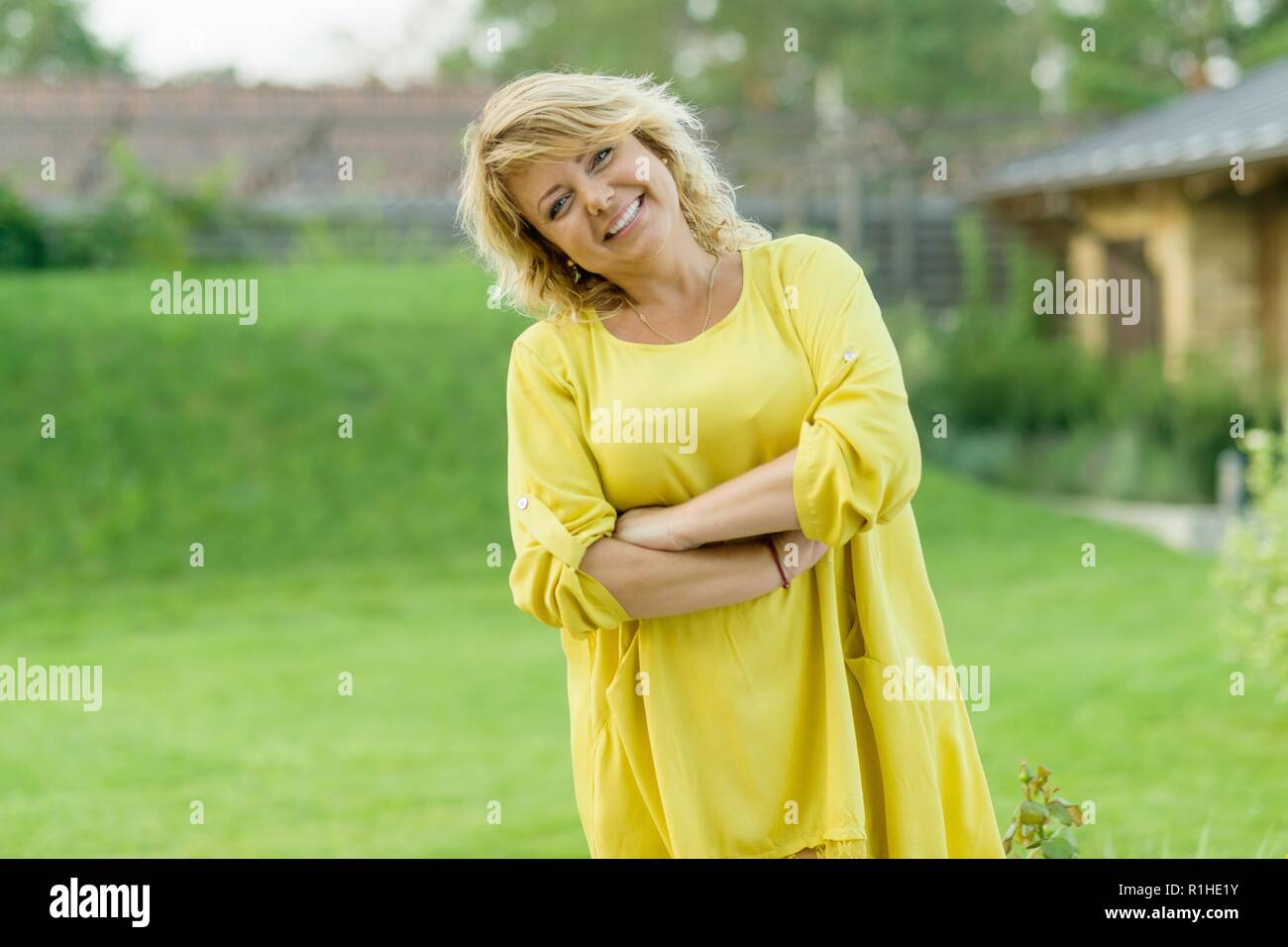 Ritratto esterno positivo della coppia di mezza età della donna, femmina con le braccia incrociate, bel sorriso, sfondo giardino. Foto Stock