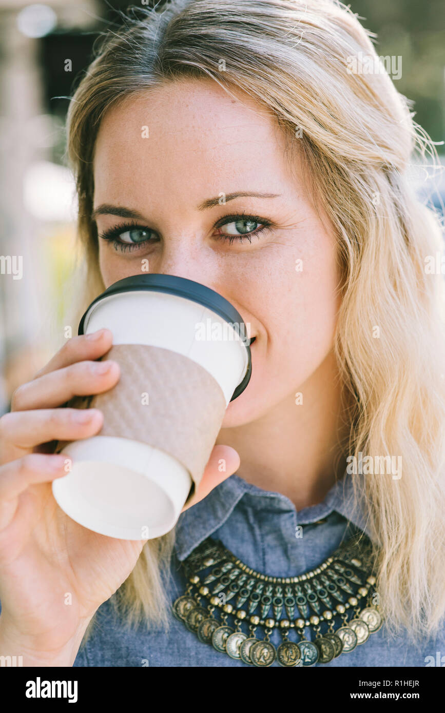 Bianco giovane femmina millenario sorseggia una tazza di caffè Foto Stock