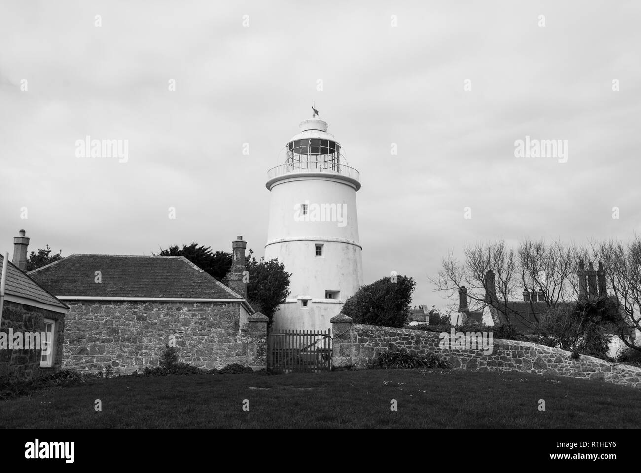L'iconico St Agnes lighthouse impostato tra gli altri edifici come il gatehouse in un giorno nuvoloso. In bianco e nero. Foto Stock