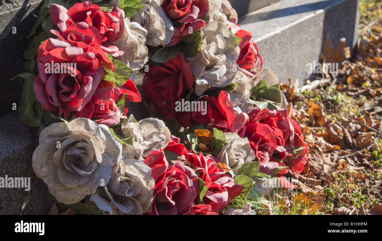 Fiori sbiaditi ai piedi di una lapide in un cimitero di Halifax. Foto Stock