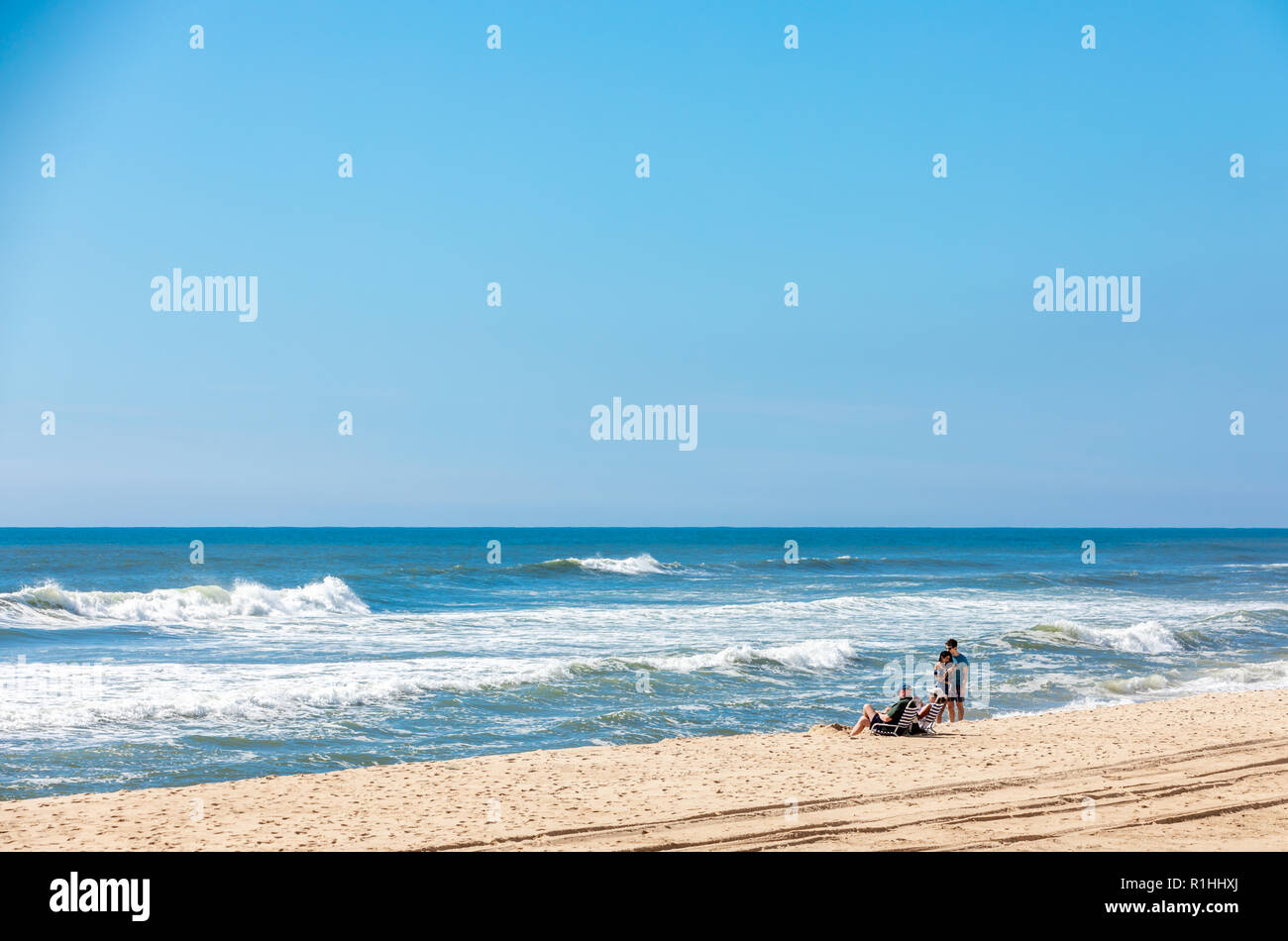 Coppie di traino in un oceano Atlantico beach, una giovane e permanente di un'altra seduta. Foto Stock